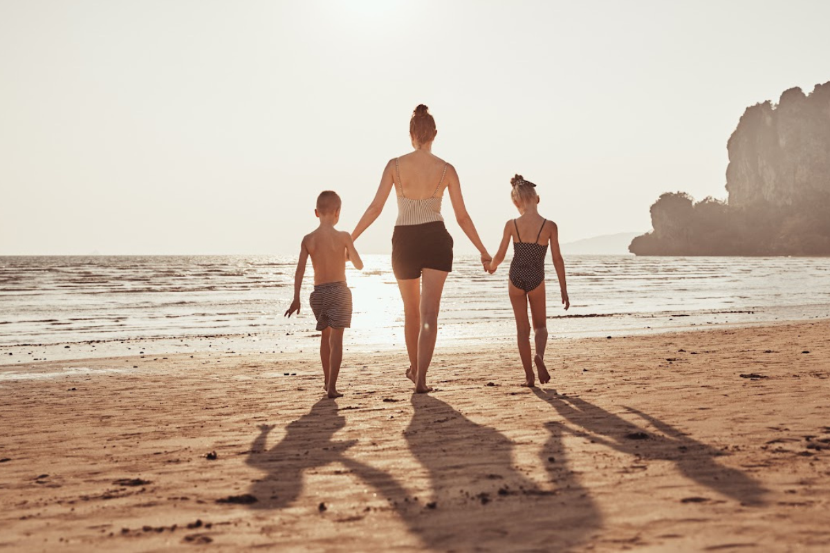 Mom and two kids walking hand in hand on the beach